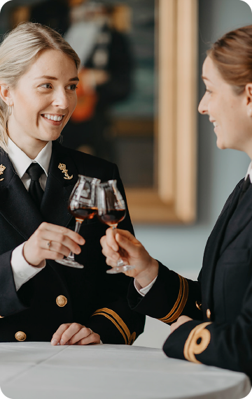 Two women cheering with a glass of rum - Royal Danish Navy